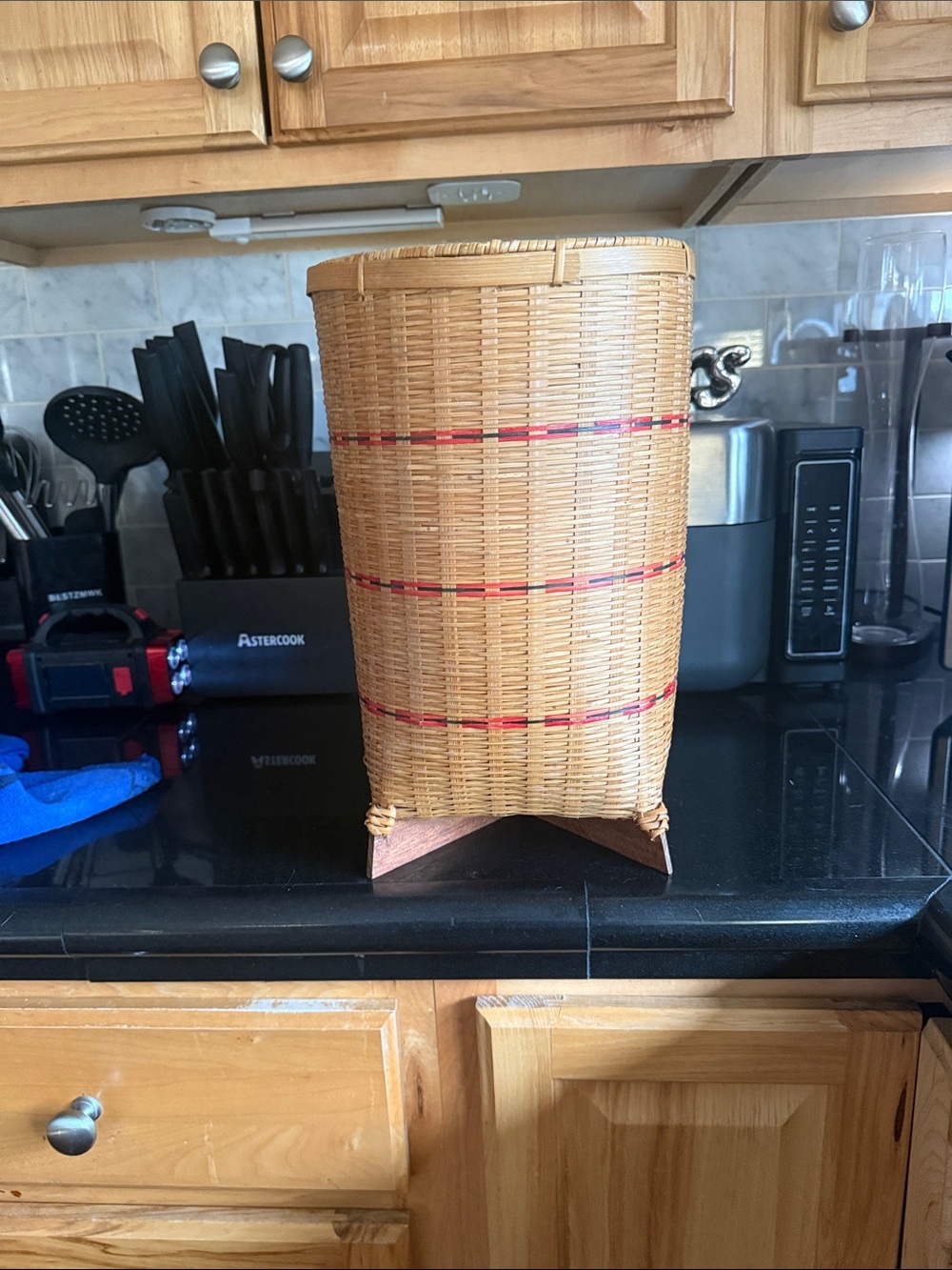A vintage cylindrical woven bamboo and rattan floor basket with feet.